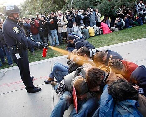 cop john pike pepper spraying a peaceful pile of subdued students at uc davis during the occupy protests in 2011