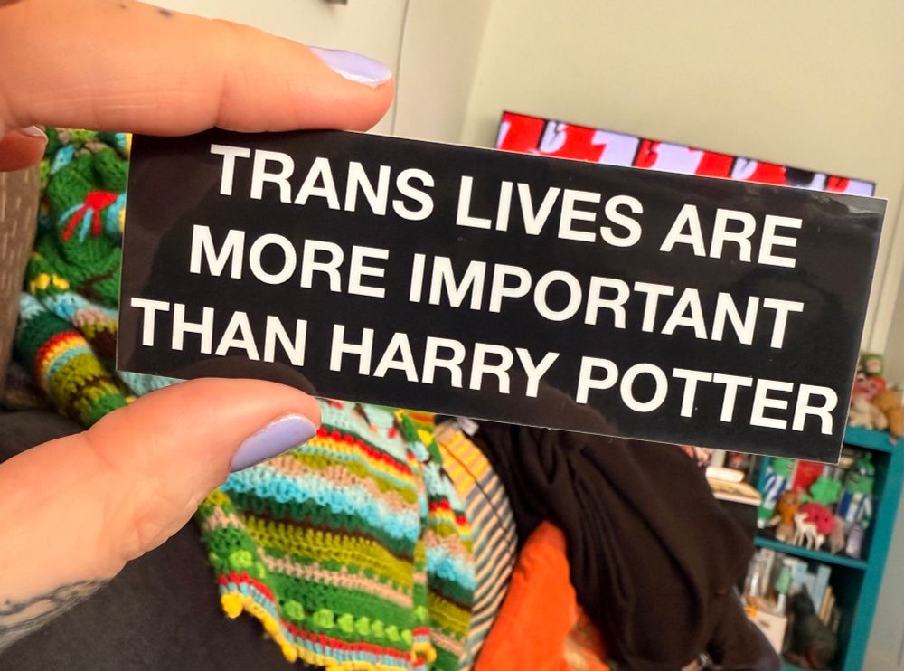A sticker from ohmygollyembroidery on Etsy that says Trans Lives Are More Important Than Harry Potter. 