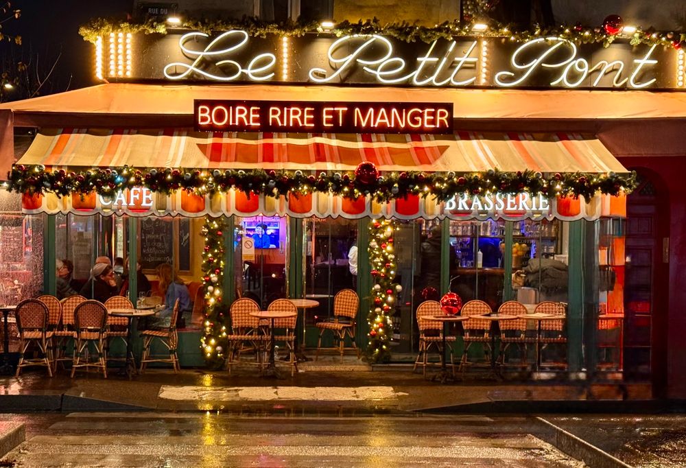 A Parisian bistro Le Petit Pont with the words “boire rire et manger” over the door.