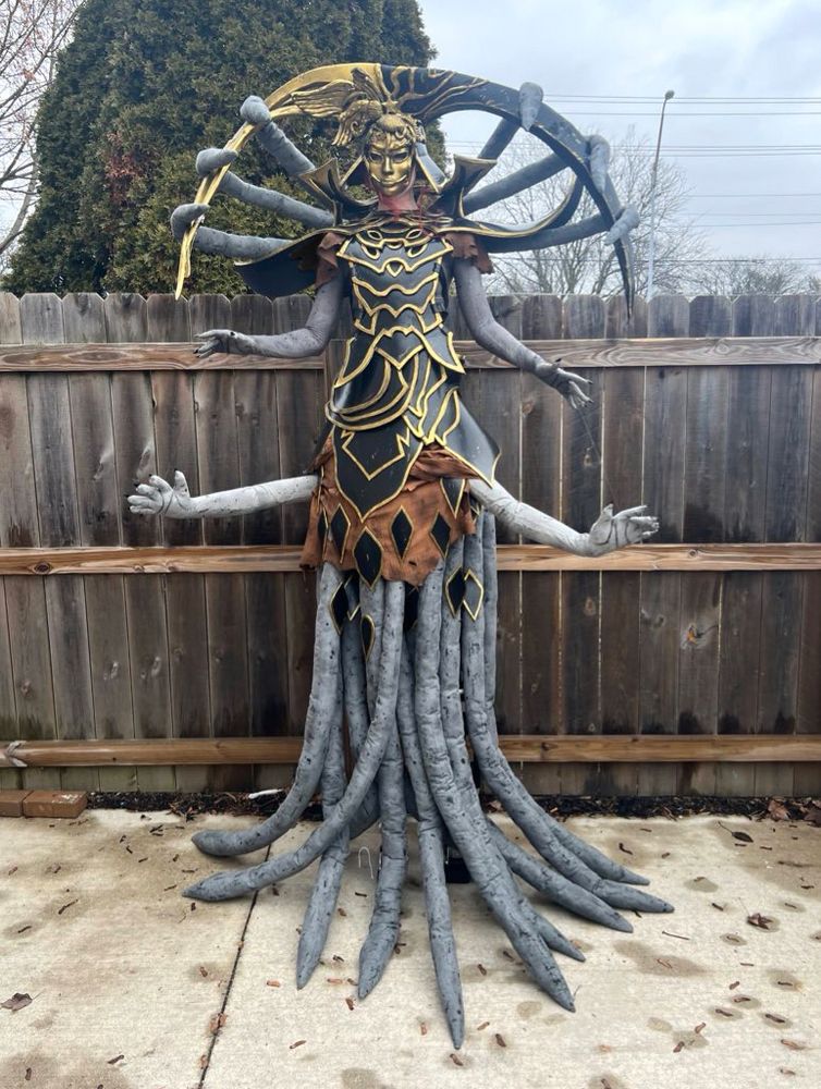 Phase in her ghilan’nain cosplay standing in front of a fence