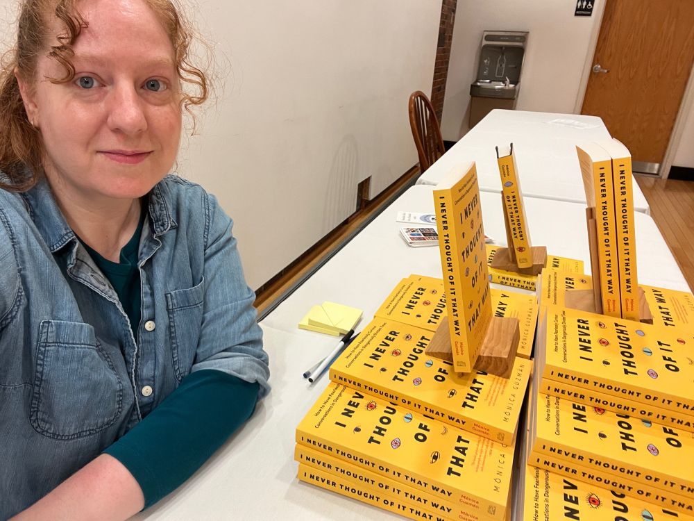 A smiling bookseller selfie with copies of I Never Thought Of It That Way