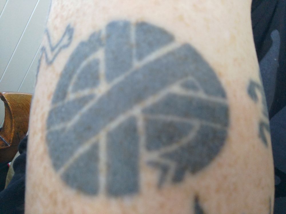 A tattoo of a Crass symbol. A confusing combination of ourobouros, cross and other symbology.