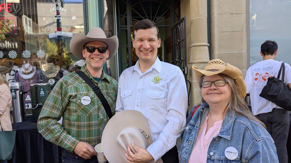 Two men and a women wearing Western style clothing and smiling for a photo