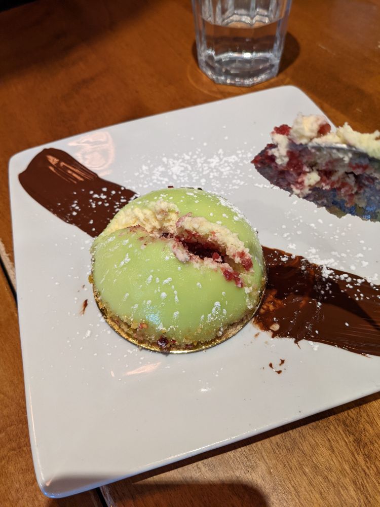 A mini dome cake with green frosting filled with white cream and red raspberry filling. It has been cut in half but the opening looks...kind of suggestive.