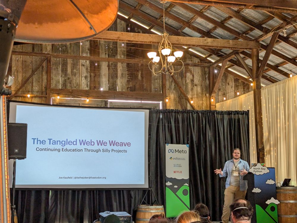 A photo of Joe on stage kicking off his talk and gesticulating.