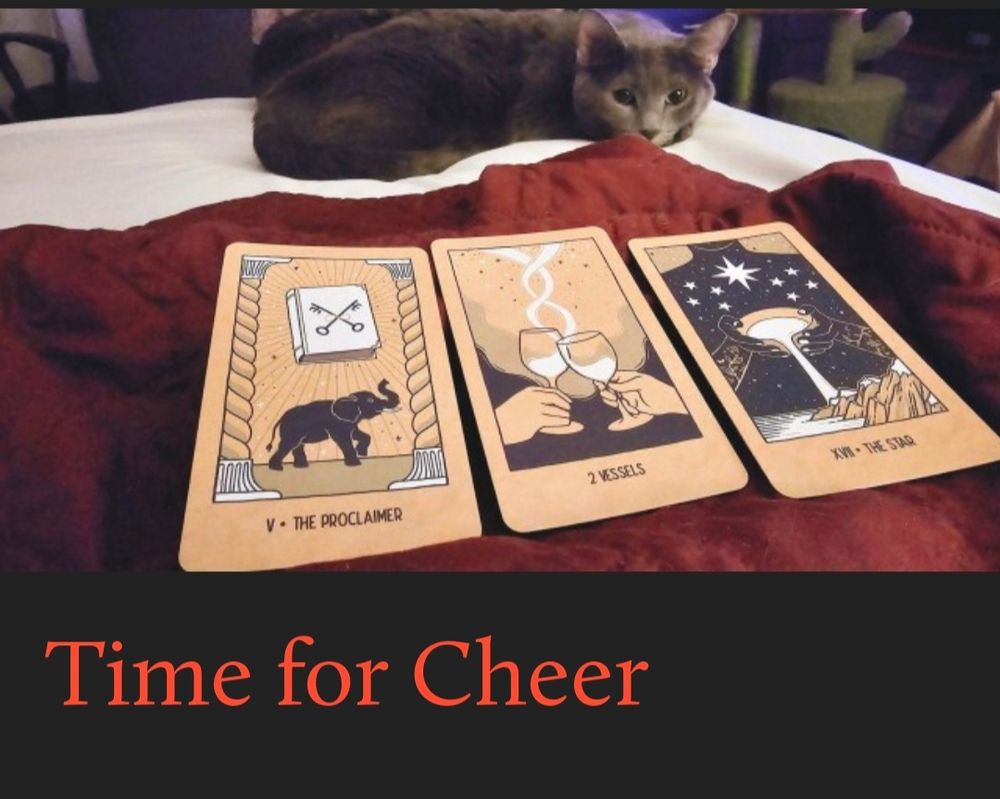 Dark grey cat, Umbreon, laying next to red blanket with tarot cards on it. The three cards are The Proclaimer, 2 Vessels, and The Star. Text below it in red says Time for Cheer.