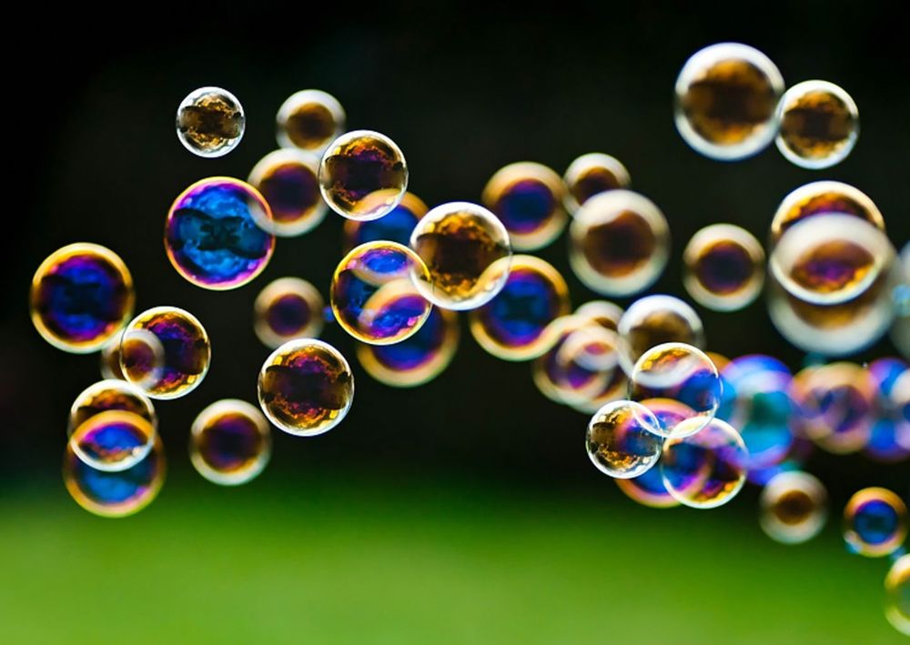 Sehr viele bunte Seifenblasen. Hintergrund ist verschwommen grün und schwarz 