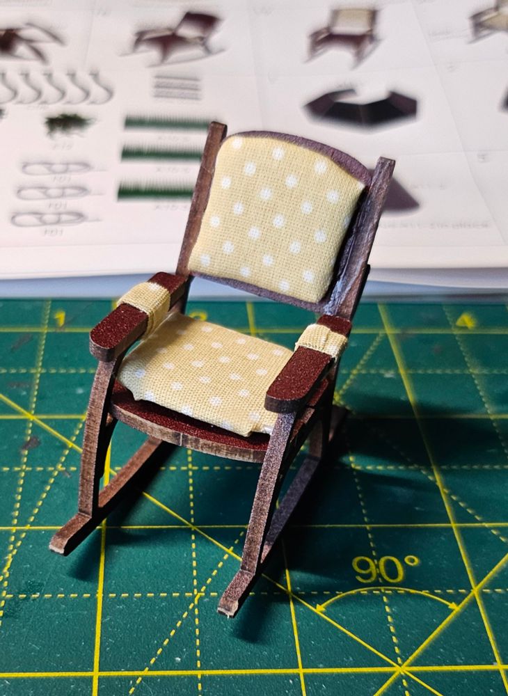 A tiny rocking chair with yellow polka-dot cushions. 