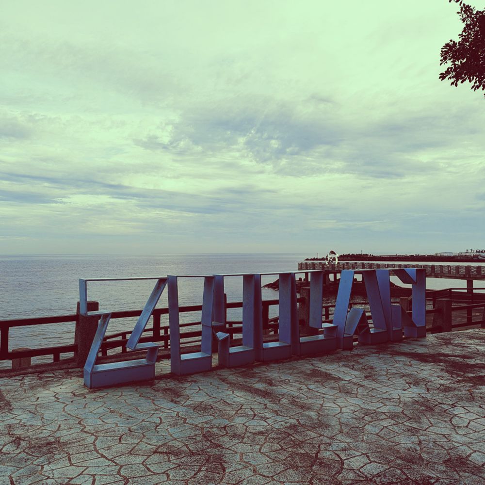 The blue metal letters spell out "Zhilan" on the water's edge, looking north across the strait towards mainland China.