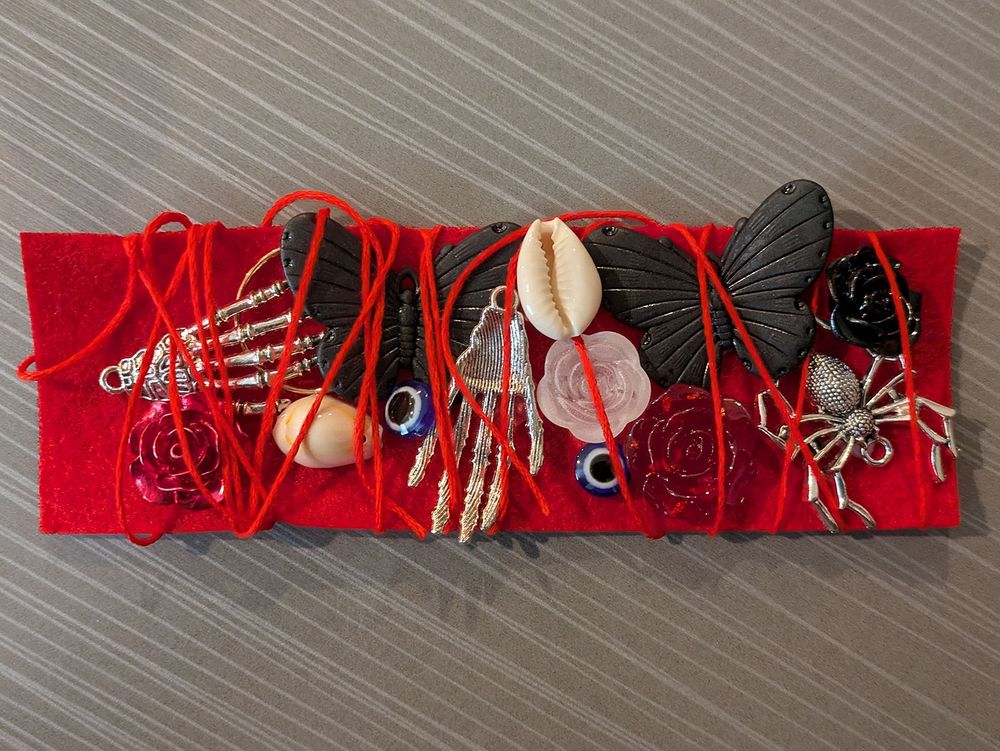 A collection of black butterfly wings, silver skeleton hands, seashells, spiders, and eyeballs wrapped in red thread, a visual representation of my vampire's utter abandonment of civilization and reversion to their primal nature.