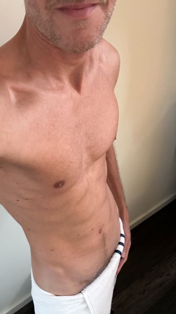 Standing with a towel barely hanging on, this morning tease shows off a lean chest, confident smirk, and that unmistakable post-shower glow. Clean, masculine, and full of promise.