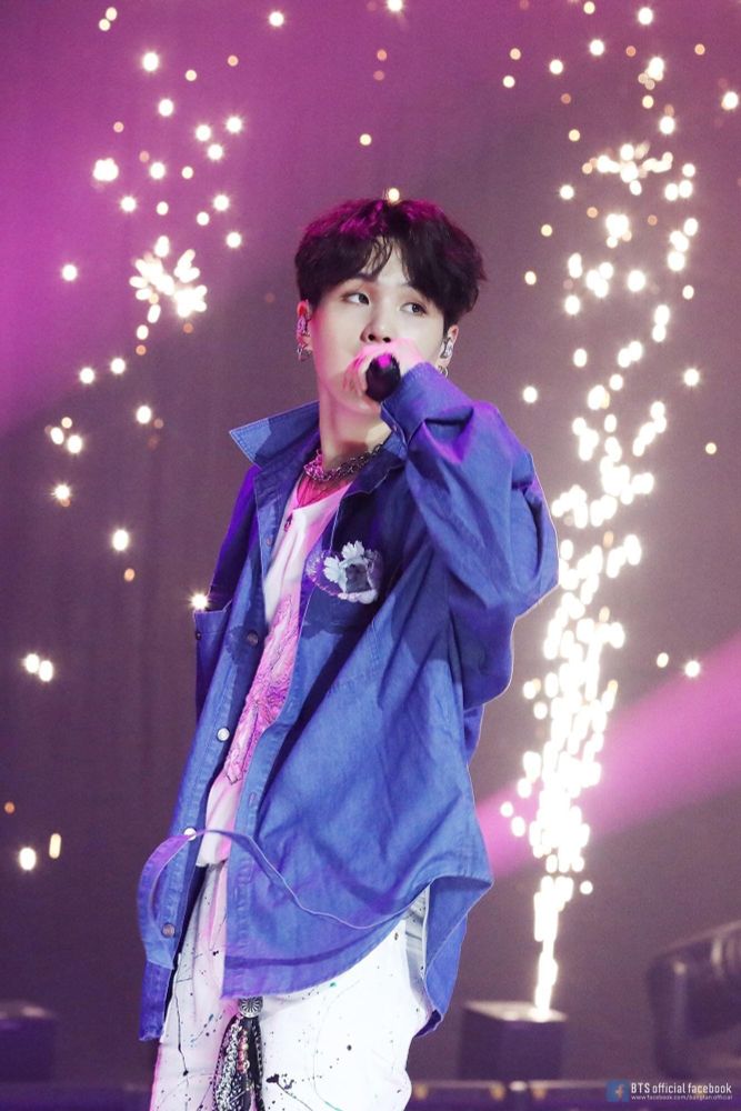 Yoongi on stage with fireworks behind him