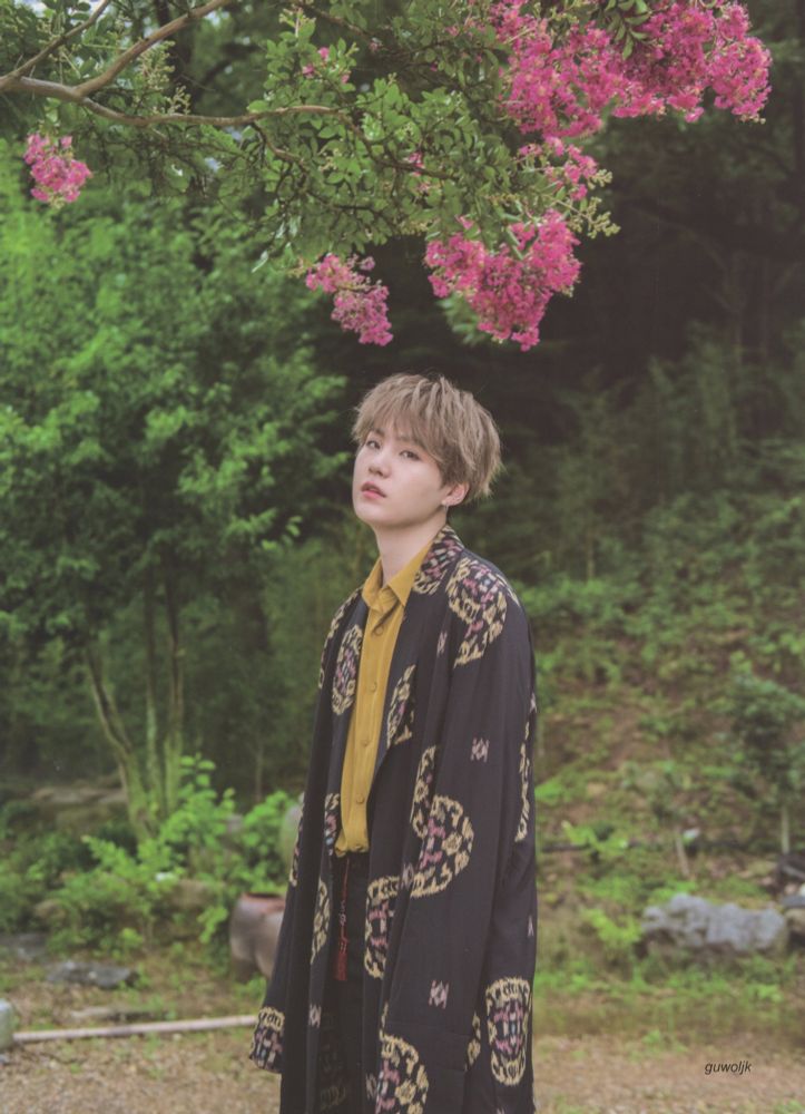 Yoongi in a  lovely casual hanbok-style robe over a mustard yellow shirt, standing under crepe myrtle it looks like. Watermelon variety I am pretty sure. There are other trees and veg behind him.   From the amazing Guwoljk scan archives. 