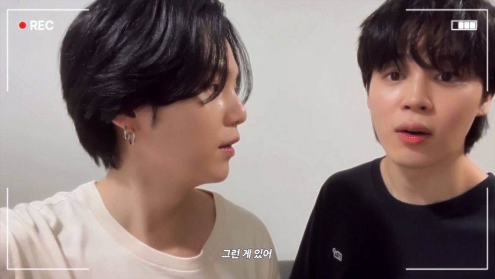 Yoongi in white t-shirt, Jimin in black, both have black hair - white background.  This time Yoongi looking at Jimin, who seems caught in a moment of semi-surprise. 