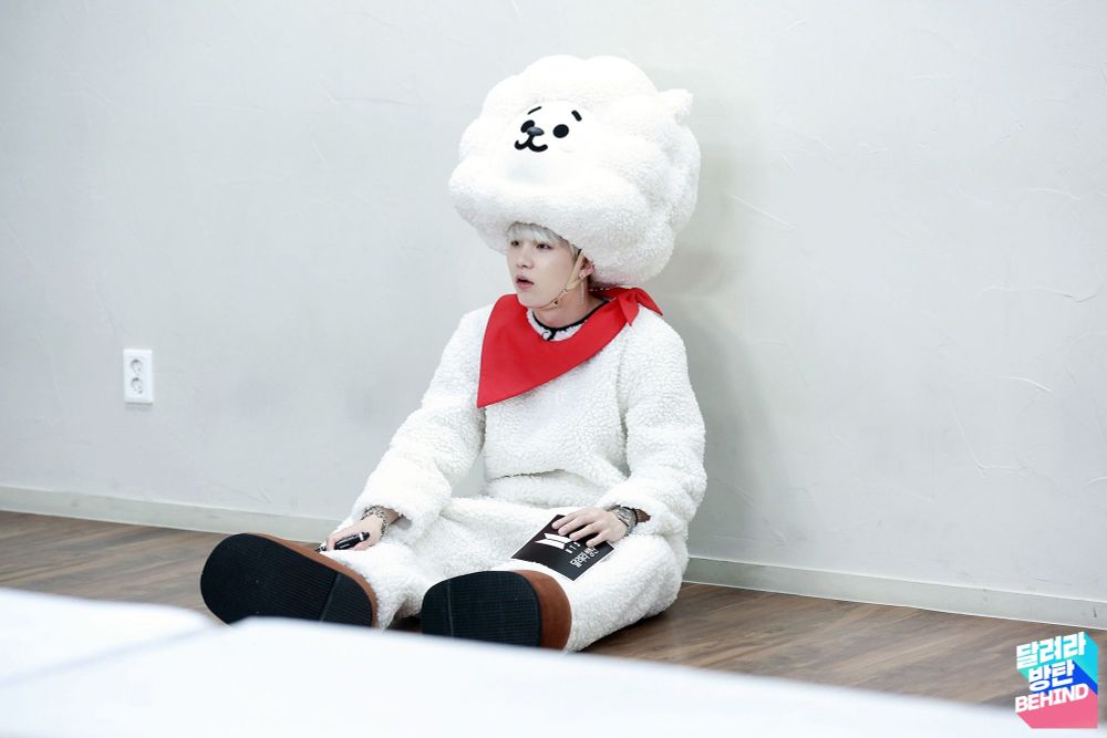 Yoongi with white hair wearing RJ costume sitting against wall and looking so cute.  Sorry Yoongi, love this. 