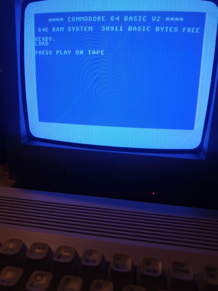 A photo of a Commodore 64Cs upper keyboard and a crt TV screen in front of it with the blue on blue basic screen displayed 