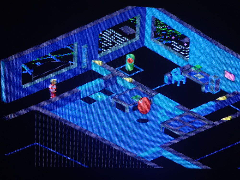 A snap from a crt TV screen of D/Gen's isometric pixel perspective of a corporate office with a red sphere bouncing about and a rotating green turret and a flashing floor title. 