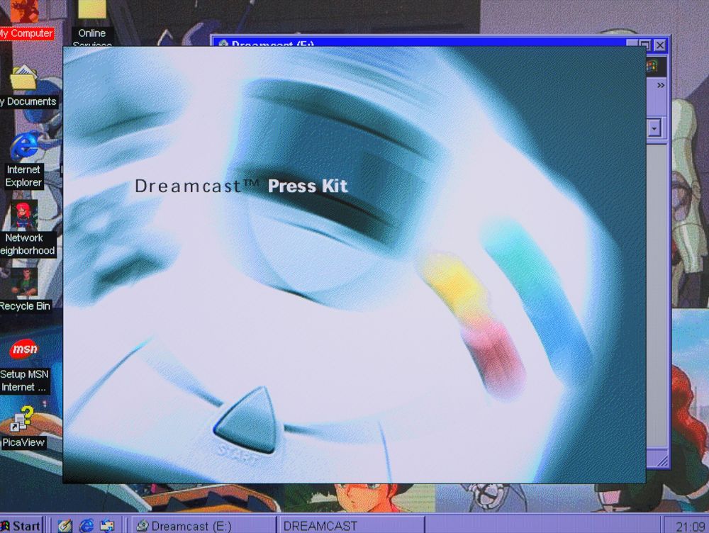 a snapshot of the autorun splash page running in Windows 98 with a blurred DC controller in the background with Dreamcast Press Kit overlaid. You click on the start button to access the greater menu.