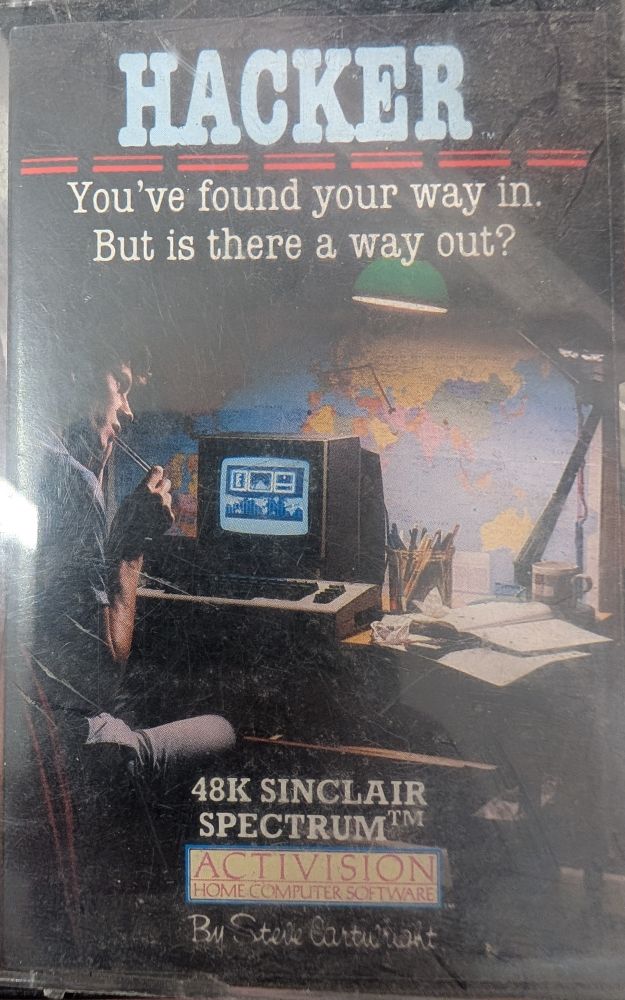 The photographic cover of Hacker for Spectrum 48k with a male teen at their computer (not a spectrum but a breadbin C64) and thoughtfully considering a techie ui with a map of the world with connecting pins on it. 