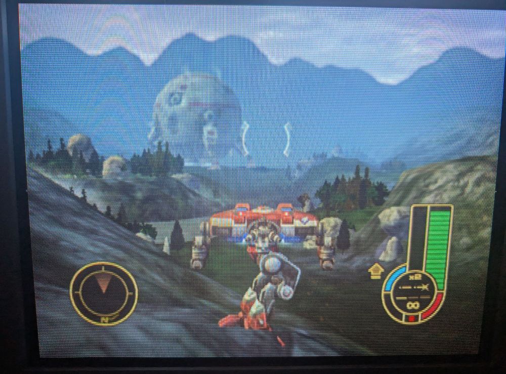 A crt screenie of a Cougar mech in profile with its upper body pivoted around to face a forested mountain valley. A huge orb like dropship can be seen through must 