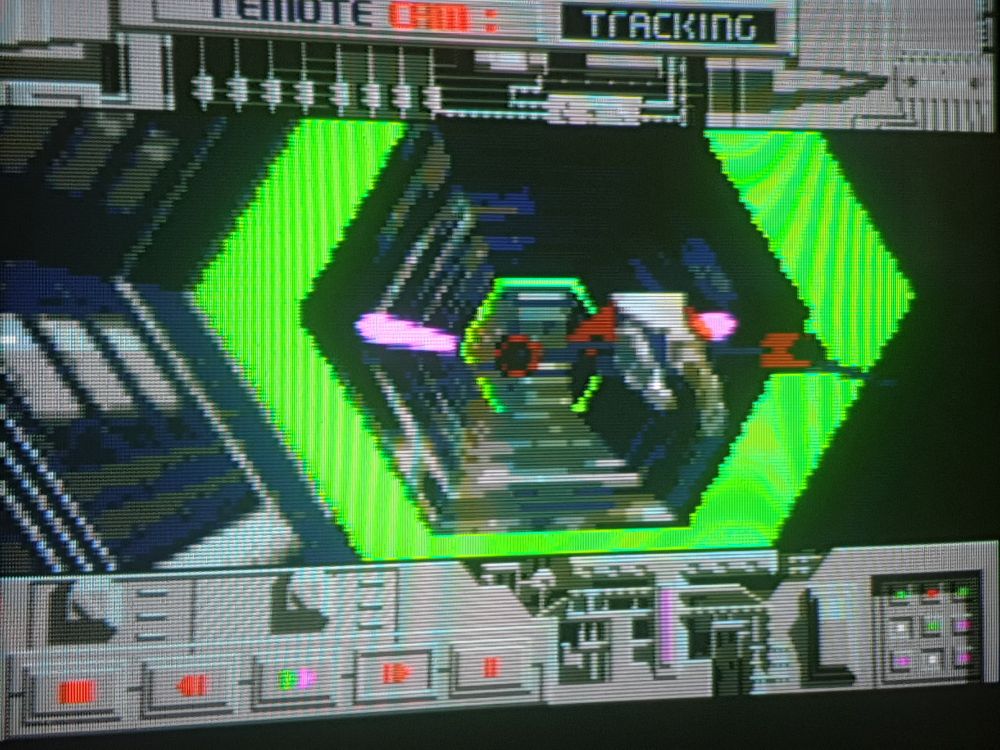 A crt screenie of the opening tunnel section with glowy green hexagonal corridors and streamed backgrounds. 