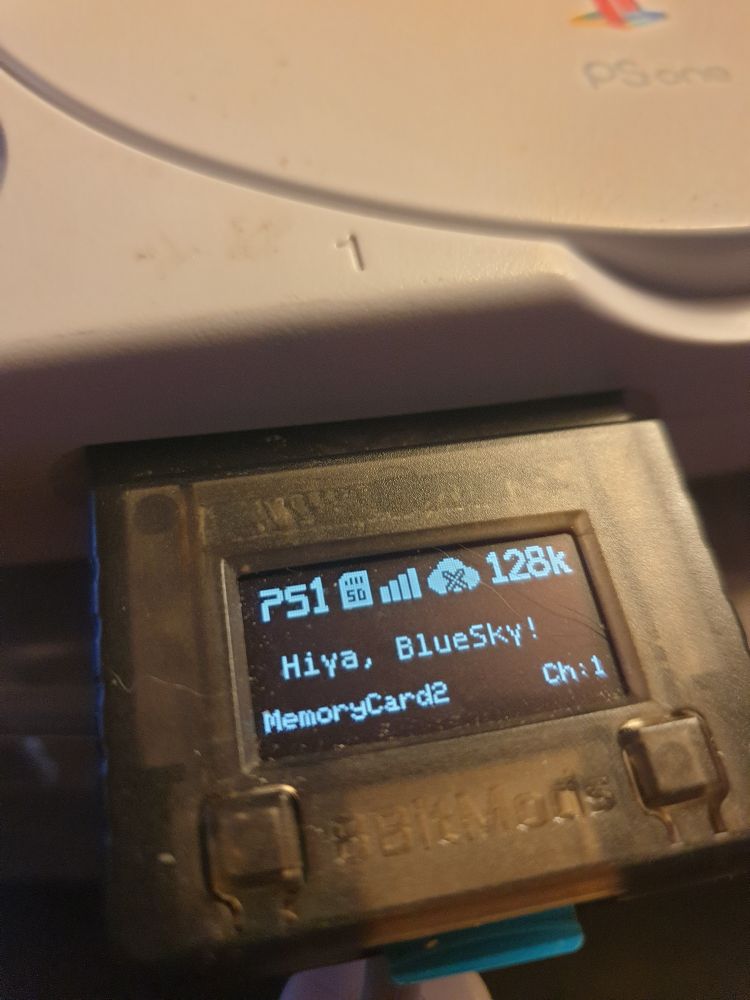 A photo of an 8bitmods pro 2 memory card plugged into a PSone with Hiya BlueSky on the screen 