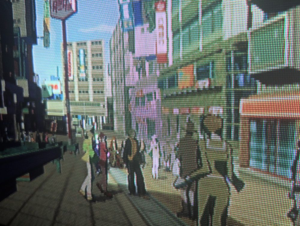 A close up crt TV screenie of a bustling pedestrian area with hip npcs dressed in funky fashion walking past stores and multi floor commercial blocks. 
