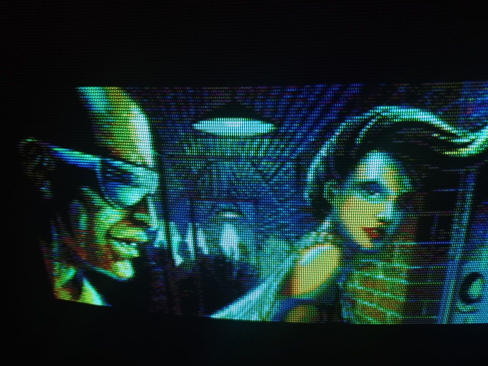 One of the illustrated cutscenes with a bald guy sporting mirrorshades in profile in a brickwork corridor with a gal sporting upswept and curled hair looking pensively at him