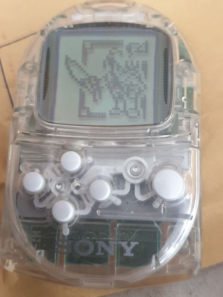 A photo of a translucent PocketStation with a pixel sprite of Squall from FF8 on the screen 