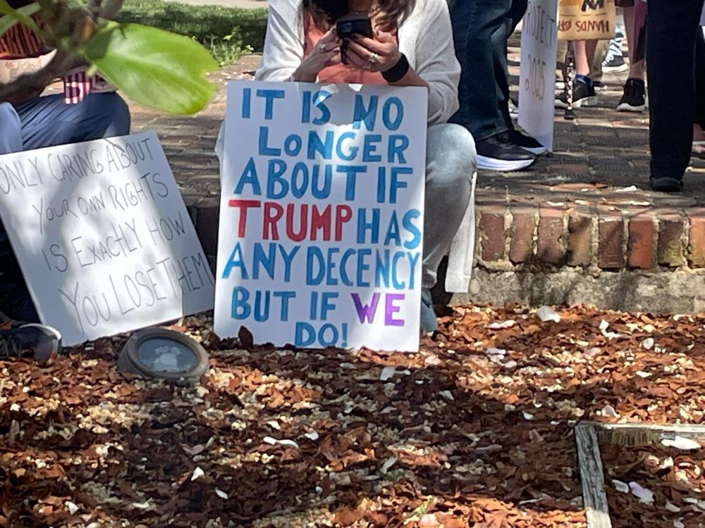 A woman with a sign that says 'it is no longer about if trump has any decency but if we do!