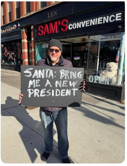 guy holding up sign ' santa - bring me a new president'