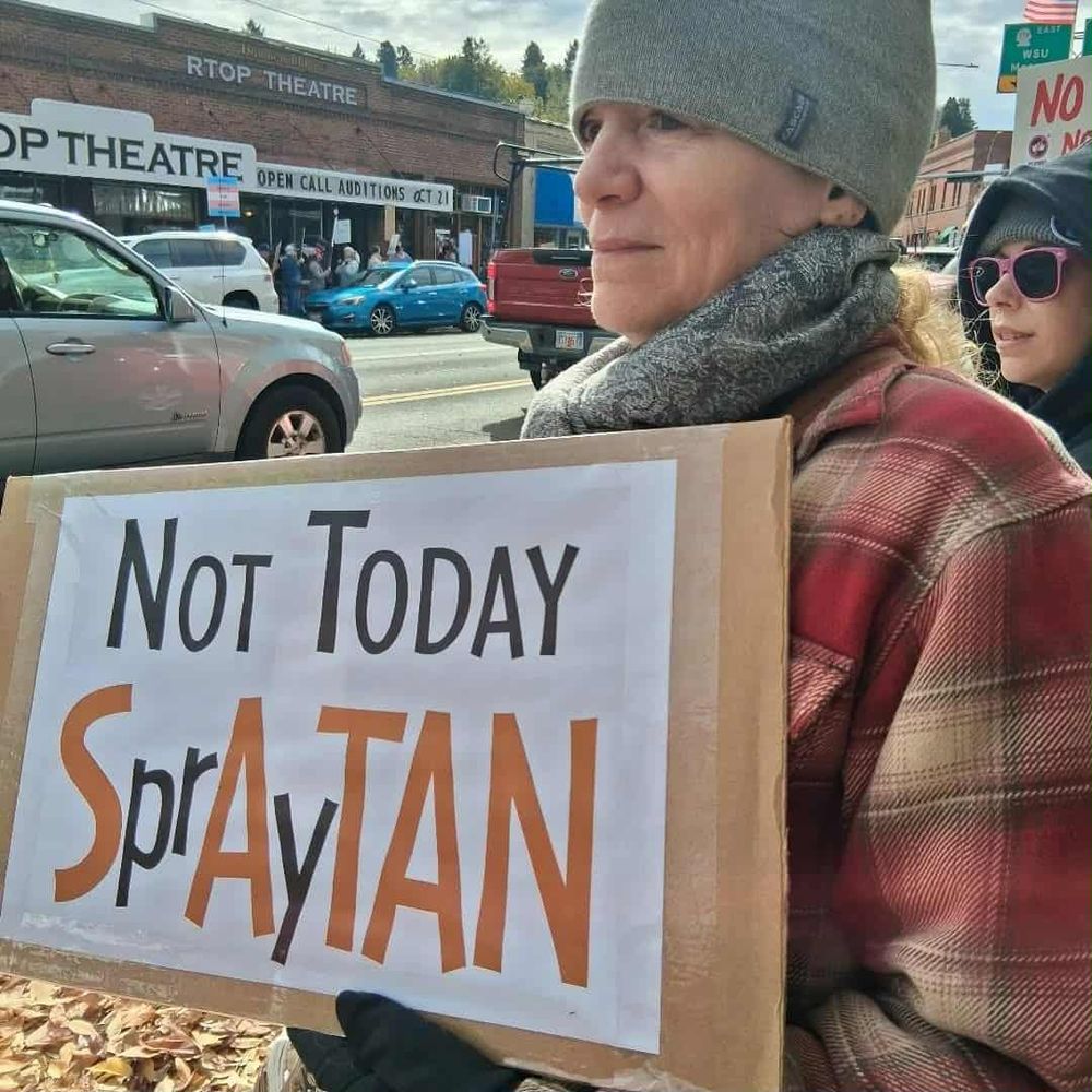a woman holding a protest sign that says two things depending on how you read it "not today spraytan" or "not today satan"