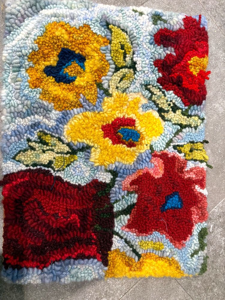 Deanne Fitzpatrick rug hooking pattern Big Red Pot of flowers, A red pot with gold and red flowers and green leaves  in an abstract design hooked on a light blue background .

