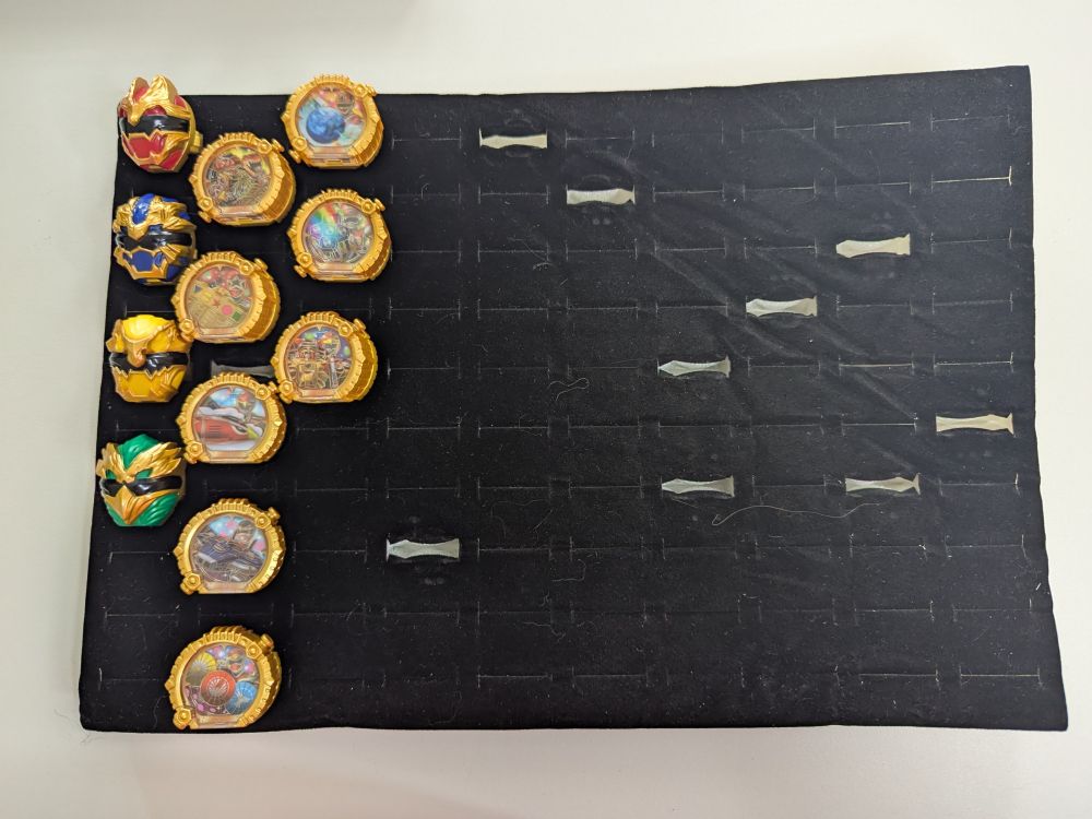 A black rectangular ring tray with a collection of Sentai Rings for the Japanese tokusatsu show No.1 Sentai Gozyuger.
Column 1: GP Sentai Rings for GozyuWolf, GozyuLeon, GozyuTyranno and GozyuEagle.
Column 2: GP Sentai Rings for Kyoryuger, Ohranger, Jetman, Megaranger, Hurricanger, Changeman, Flashman, Liveman