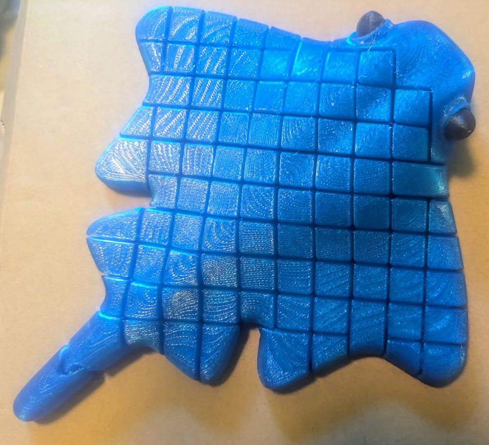 A bright blue articulated, 3d printed ray with bulging black eyes