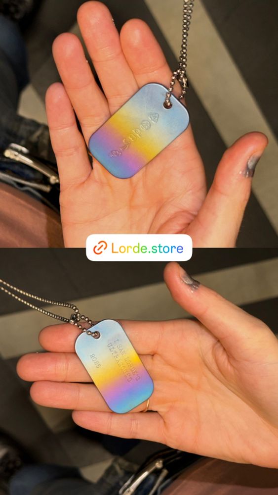 Lorde holding the dog tag merch necklace on her hand