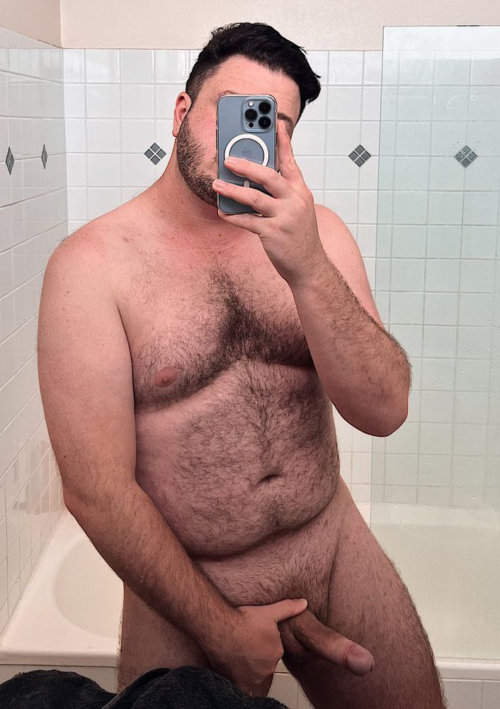 a hairy guy with an erection taking a selfie in the bathroom mirror