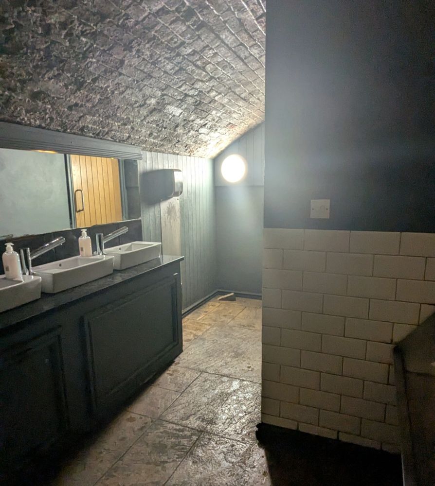 A low lit public toilet with one massive spotlight for no reason 