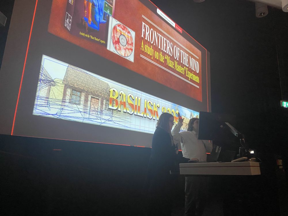 Picture of a presentation in front of a slide showing the title cards for itch.io horror games Frontiers of the Mind and Basilisk 2000.
