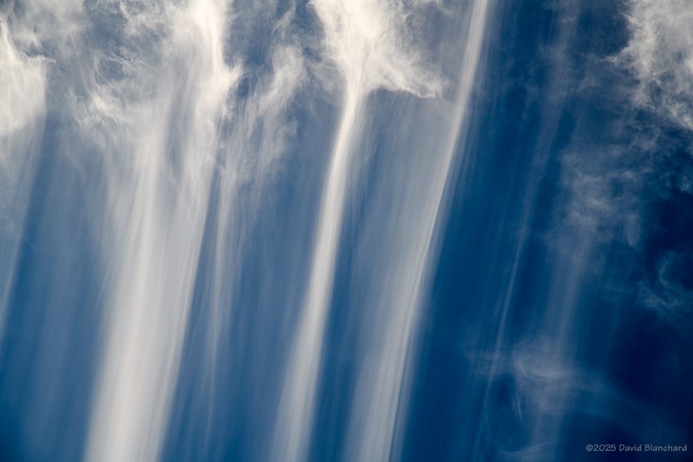 A tight telephoto image showing detail and structure of the trails of falling ice crystals from the cirrus floccus clouds above.