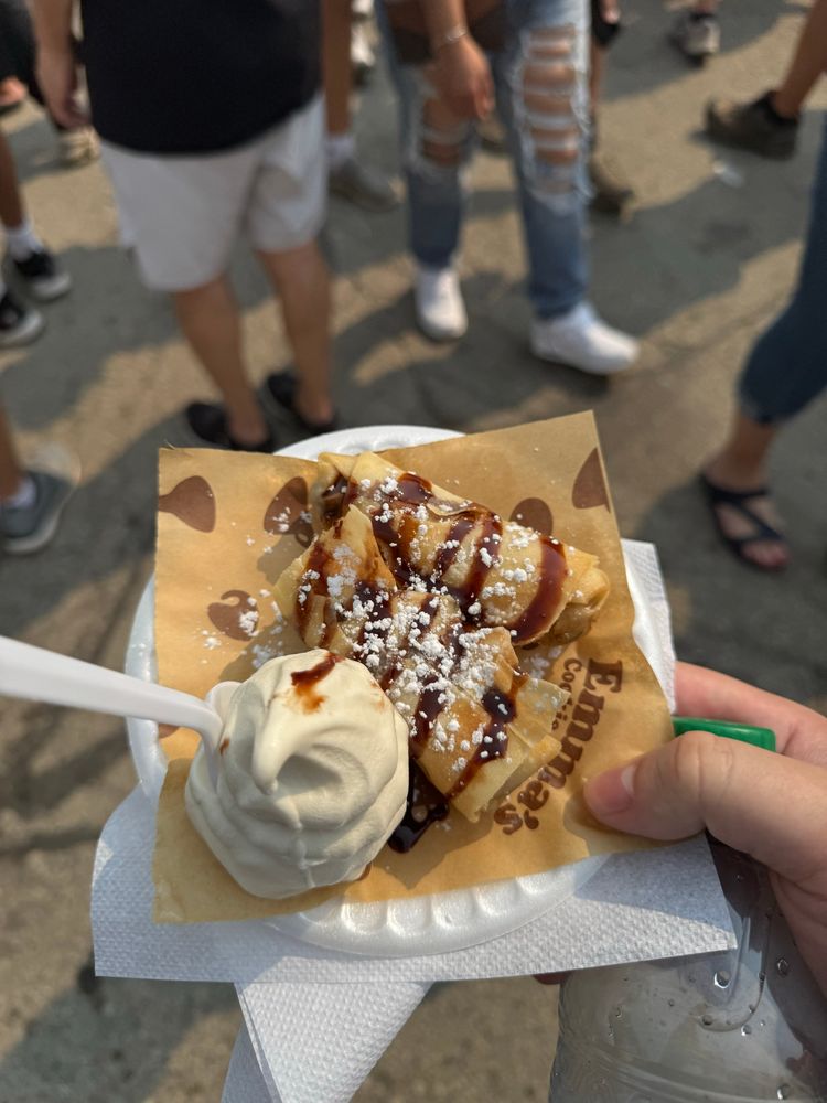 What appears to be an egg roll with chocolate sauce drizzled over it and a small amount of vanilla soft serve ice cream beside it. It's actually "deep-fried cookie dough"