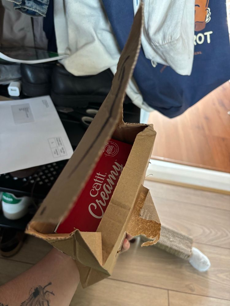 The top of a ripped open parcel, showing a box that says “catit creamy”