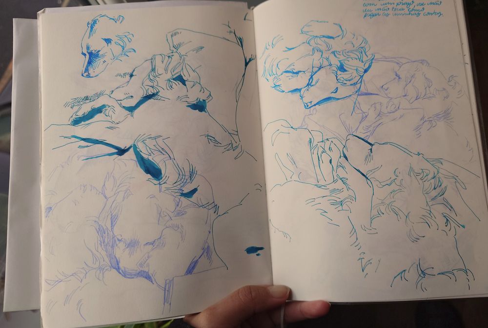 A hand holding an A5 sketchbook open. The pages are cream, and on it there's 6 different sketches of dogs sleeping. Two are made with periwinkle pencil, other two in turquoise ink and the last two in cyan ink.