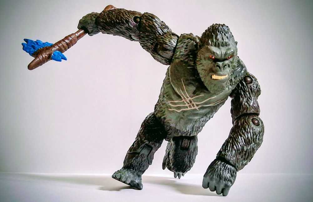 King Kong, snarling at his foe, charging with his axe in his right hand and his left on the ground.
