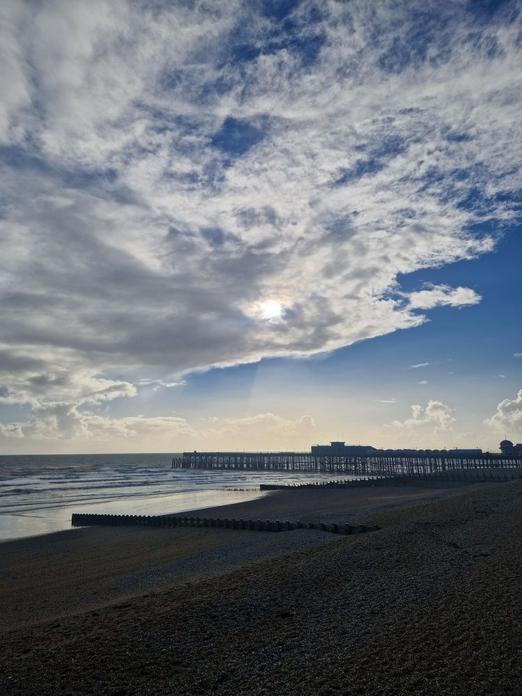 Pier under cloud, sun and blue sky. 