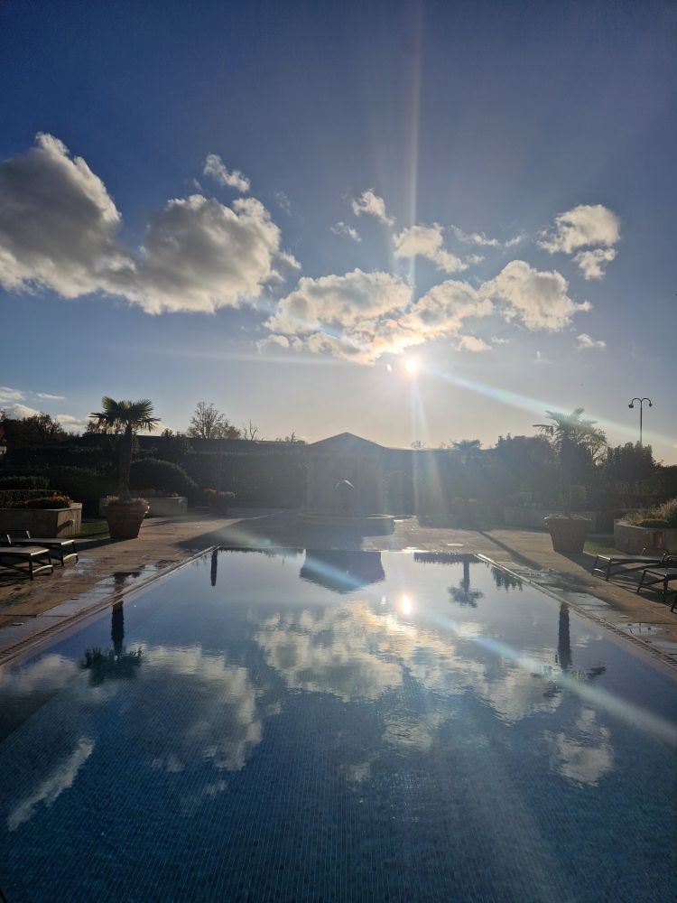 Outdoor pool at spa with clouds and sun reflected. 