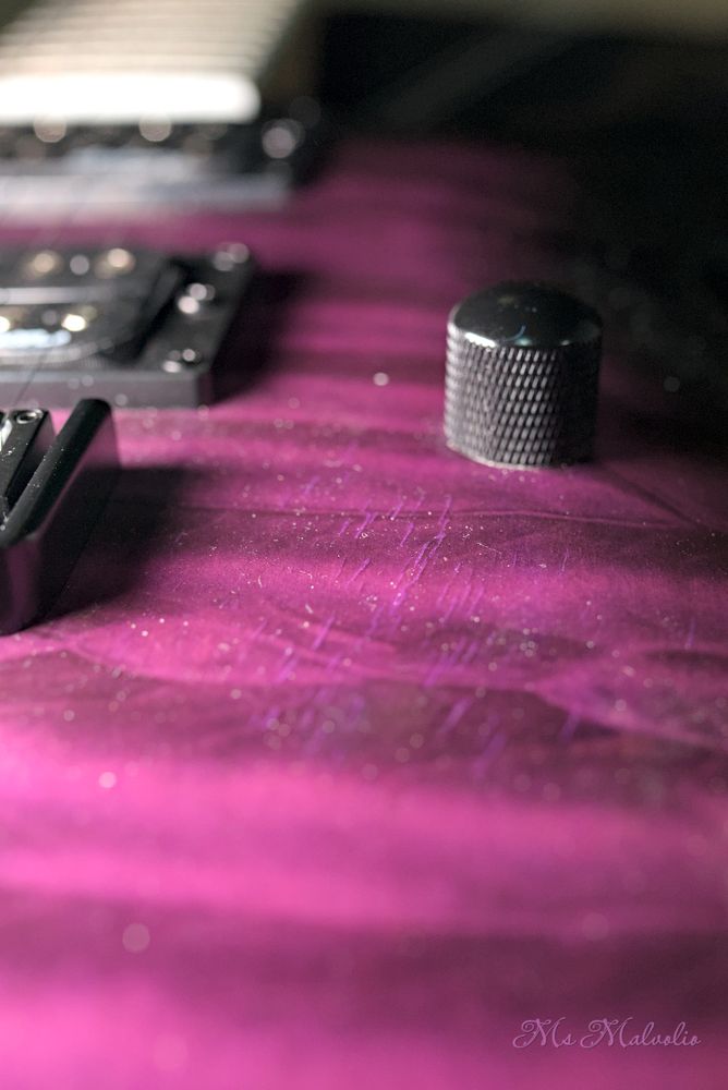 A close up of a guitar just below the bridge area, showing cracks and dents slowly accumulating due to the instrument being played while in VR.