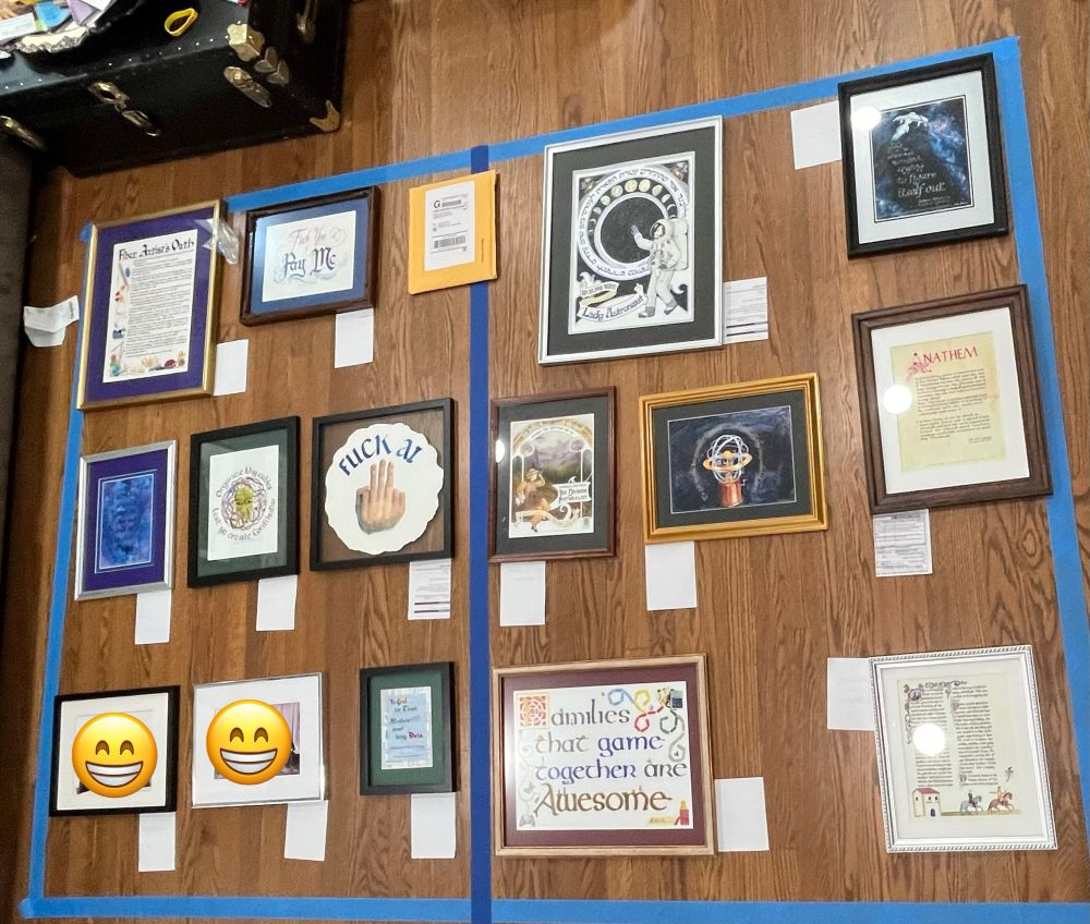 15 framed prints and originals (including 2 stunt framed photos of children that are the correct size to replicate 2 framed originals currently in a basement in Seattle, not in an attic in Chicago) laid out on a wood floor in two panels approximated by blue tape.