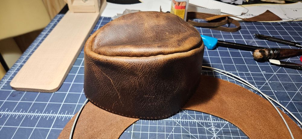 The crown of a leather cowboy hat sitting on a table.