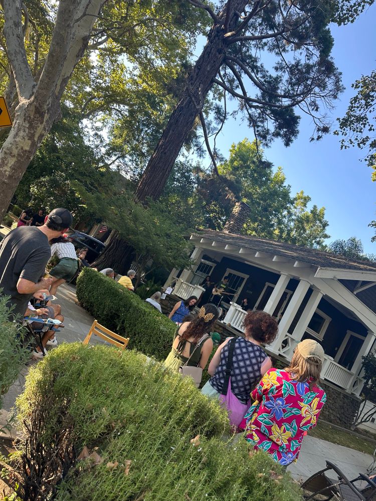 A view of a band playing on a front porch with neighbors gathered to listen